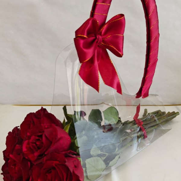 Bouquet of red roses wrapped in clear plastic with a red ribbon handle