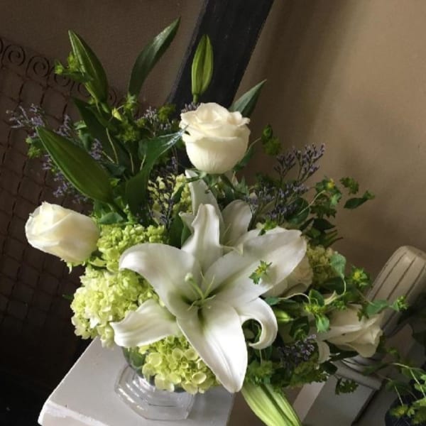 White lilies and roses arranged in a glass vase