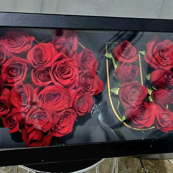 Red roses arranged in a black framed display with gold lettering