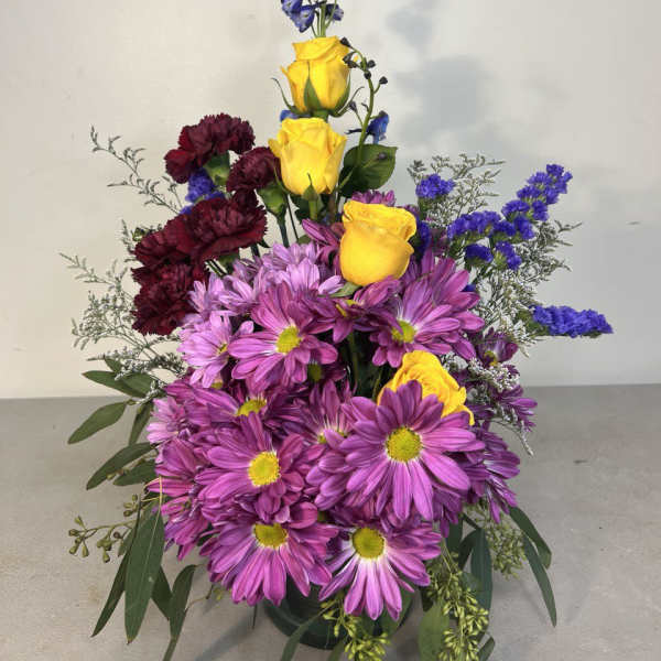Tall bouquet of purple daisies, yellow roses, and dark red carnations