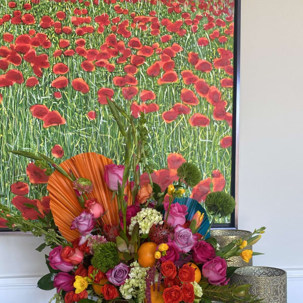 Colorful floral arrangement in a gold pedestal vase with roses and oranges