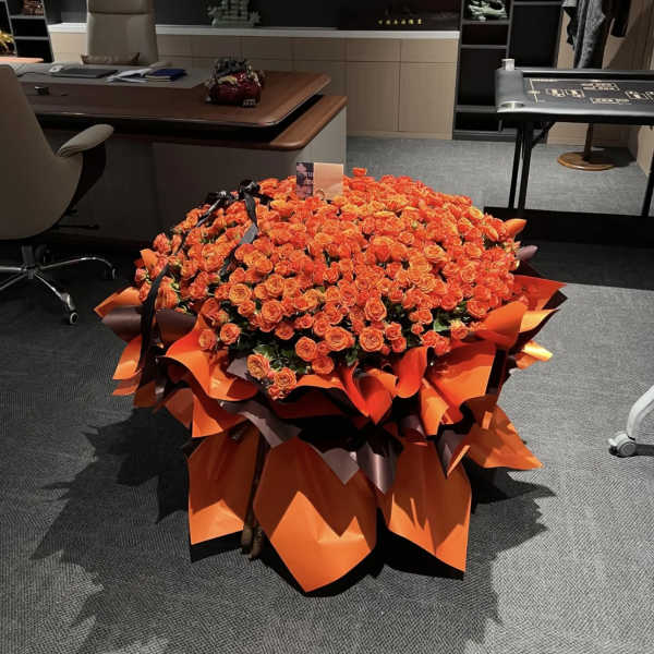 Large bouquet of orange roses wrapped in bright orange paper