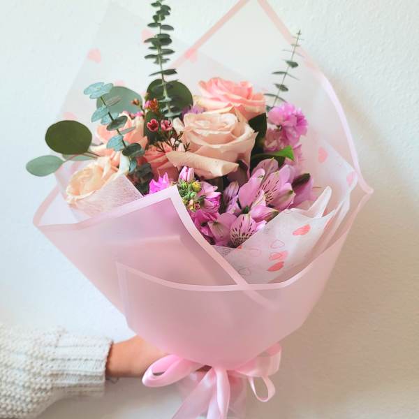Pink and peach bouquet of roses and alstroemeria wrapped in pink paper