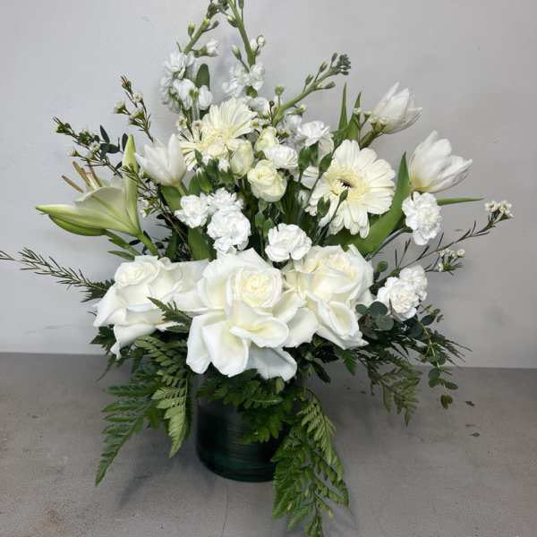 White roses and lilies arranged in a dark vase