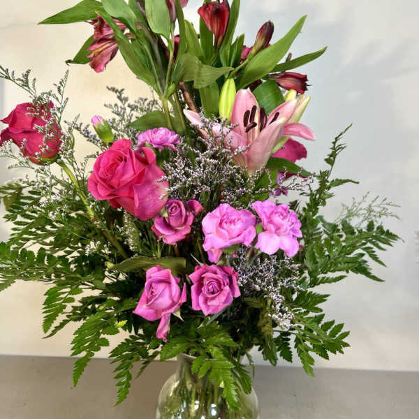 Pink roses and lilies arranged in a clear glass vase