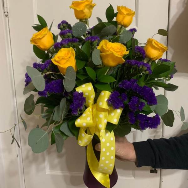 Bouquet of yellow roses and purple filler flowers with a yellow polka-dot ribbon