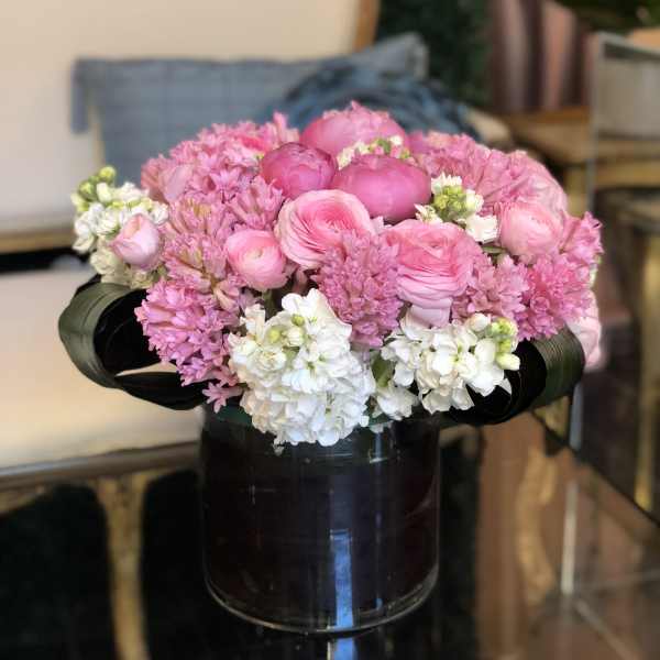 Pink and white flower arrangement in a dark glass vase