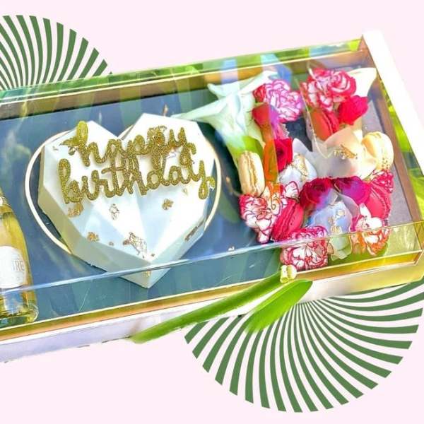 Gift box with a heart cake, flowers, and a bottle of champagne