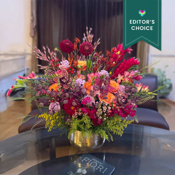 Colorful mixed bouquet in a gold vase on a table