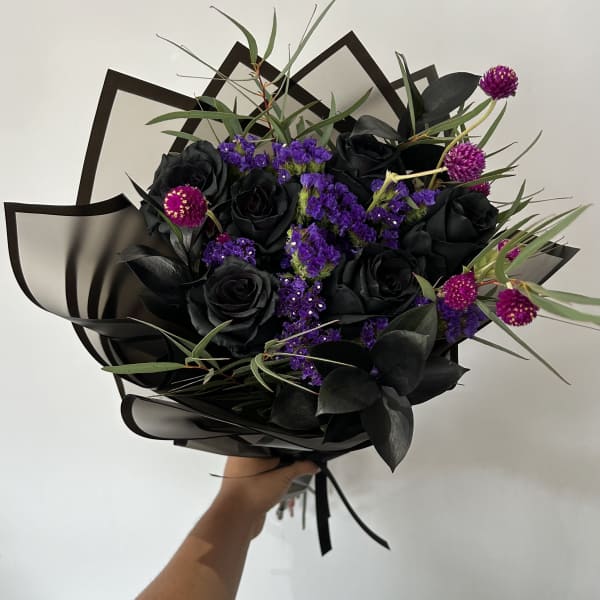 Black rose bouquet with purple filler flowers and dark foliage