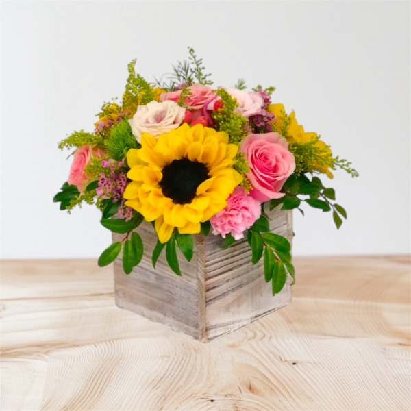 Mixed bouquet with a sunflower and pink roses in a wooden box