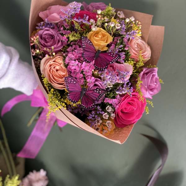 Bouquet of multicolored roses with two purple butterfly decorations