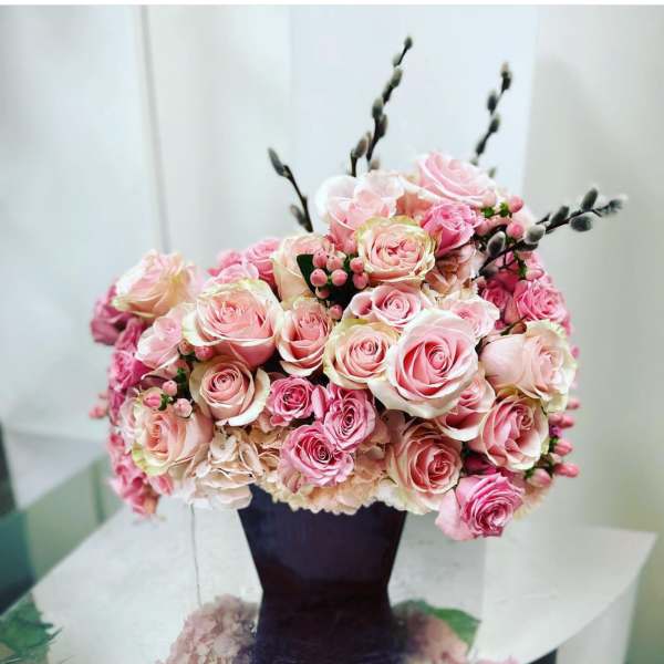 Pink and blush roses arranged in a dark vase