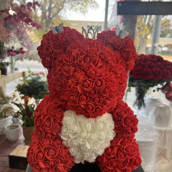 Red rose teddy bear with a white heart on a black base