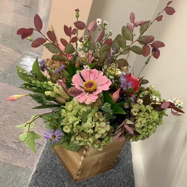 Mixed bouquet with pink and purple flowers in a wooden box