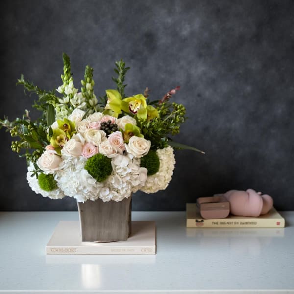 Mixed floral arrangement in a square vase with white and pale pink blooms