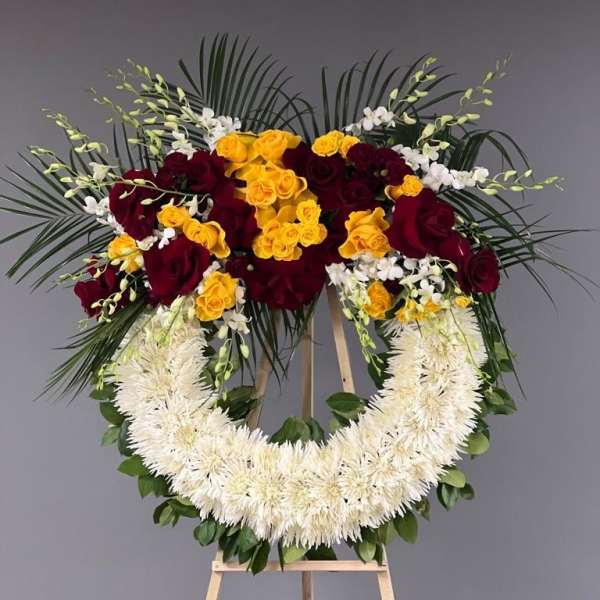Standing floral wreath with red and yellow roses on an easel