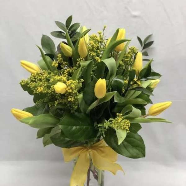 Yellow tulips arranged in a clear glass vase with a yellow ribbon
