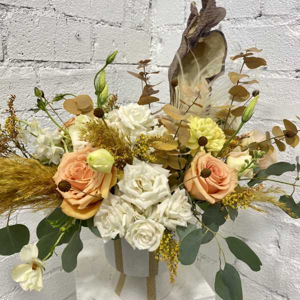 Peach and white rose arrangement in a white hatbox with dried accents