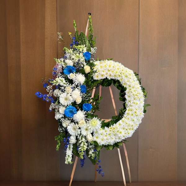 Large floral wreath on an easel with white and blue flowers