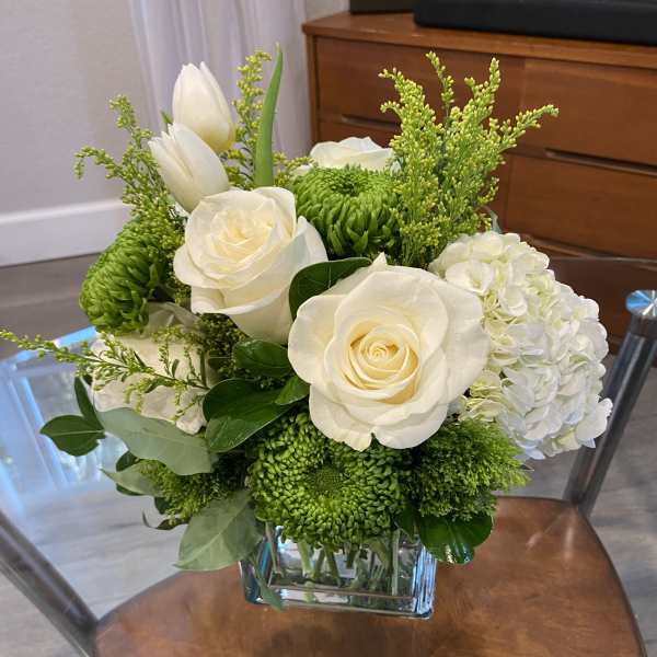 White roses and green chrysanthemums in a square glass vase