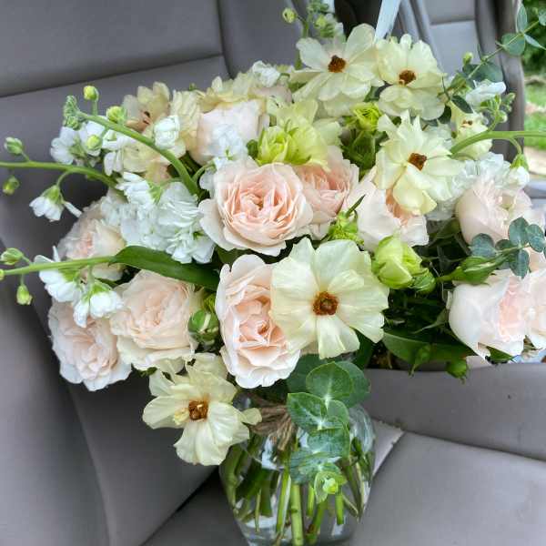 Blush roses and pale cream flowers in a glass vase