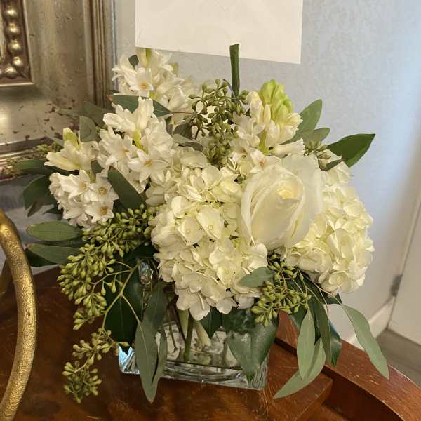 White floral arrangement in a clear glass vase with a card holder