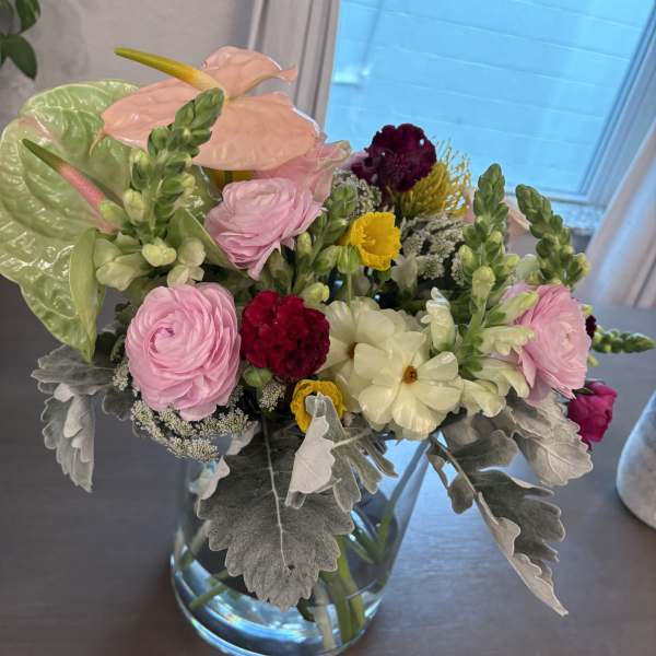 Mixed bouquet in a clear glass vase with pink, white, and yellow blooms