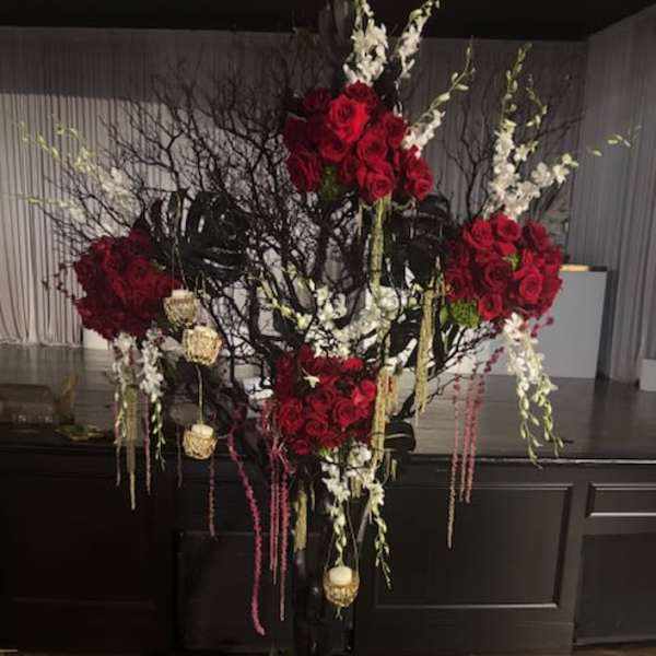 Tall floral arrangement with red roses and white blossoms on dark branches