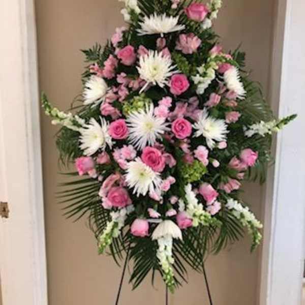 Standing floral spray with pink and white flowers on a black easel