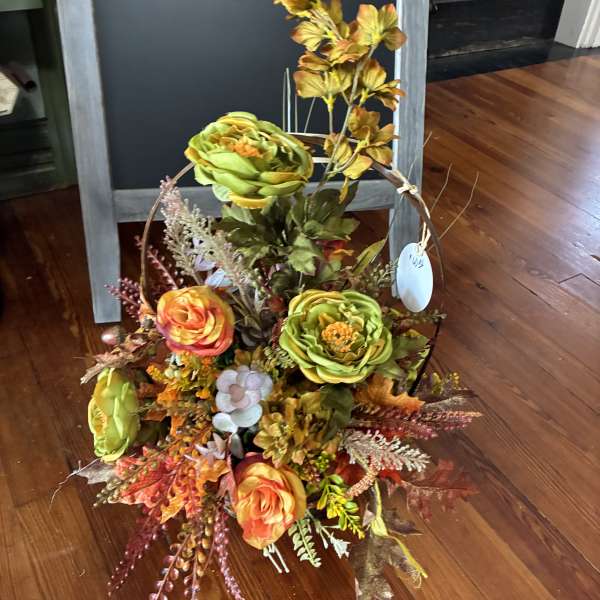 Autumn floral basket with orange and green blooms and fall foliage