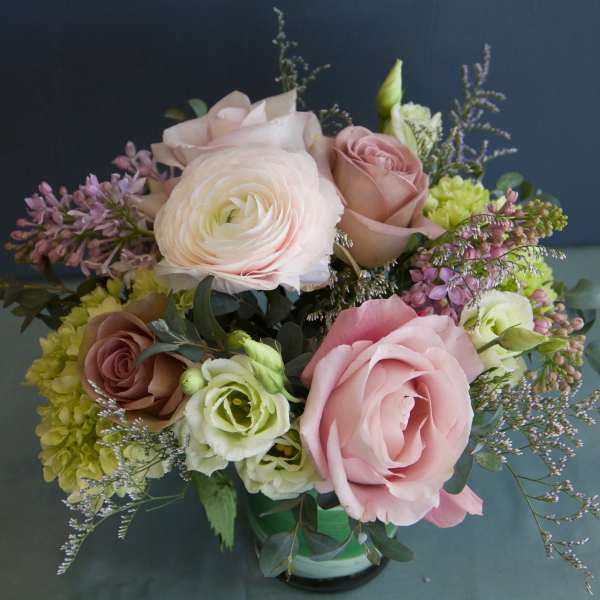 Bouquet of pink and white roses with purple filler flowers in a glass vase