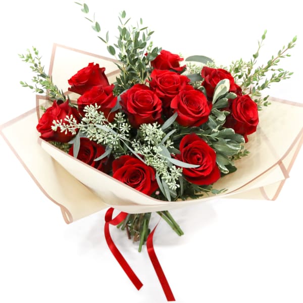 Bouquet of red roses wrapped in cream paper with a red ribbon