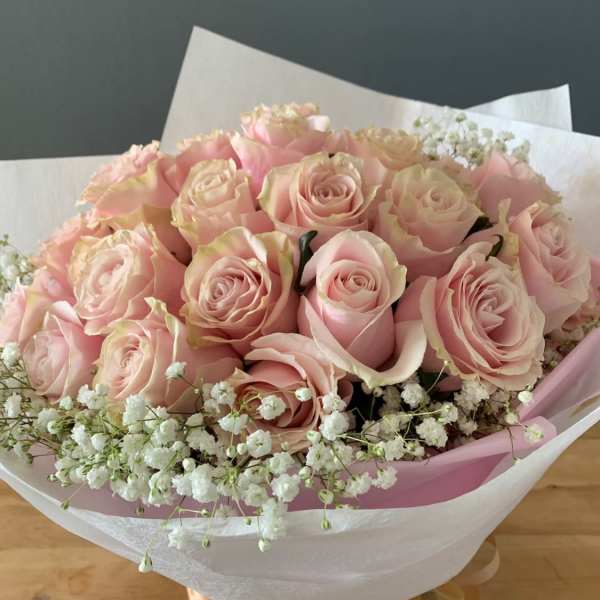 Bouquet of pale pink roses with white baby's breath in pink and white wrap