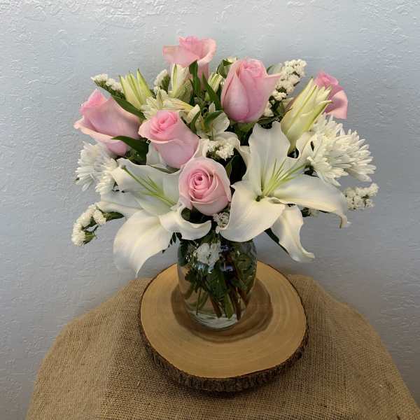 Pink roses and white lilies arranged in a glass vase