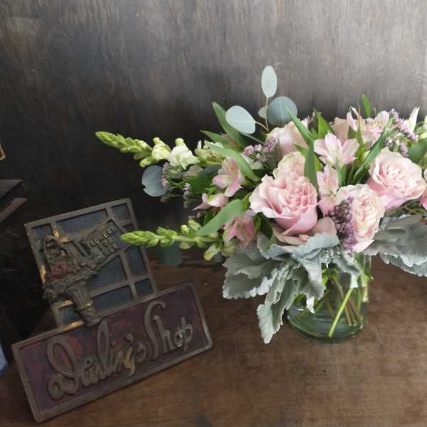 Low glass vase of pink carnations, alstroemeria, and white snapdragons with soft gray foliage.