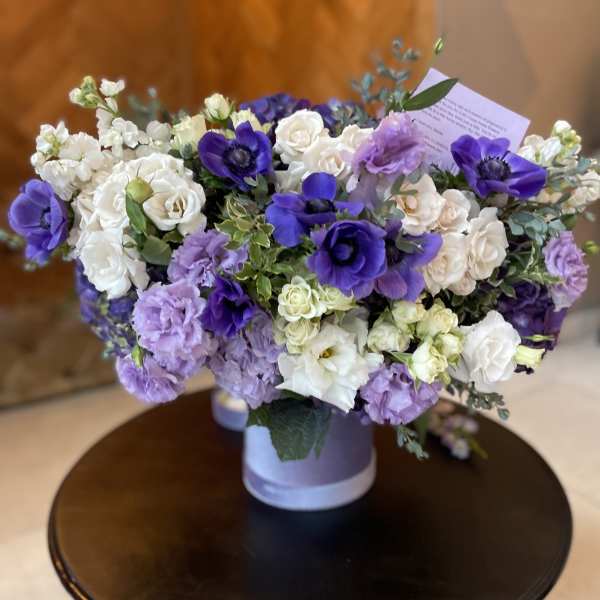 Bouquet of white and purple flowers in a lavender container