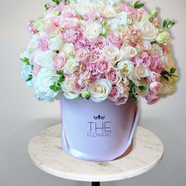 Large pastel bouquet of pink and white roses in a lavender hat box