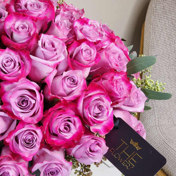 Bouquet of pink roses in a glass vase with a black tag