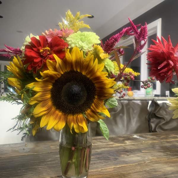 Mixed bouquet with a large sunflower in a glass vase
