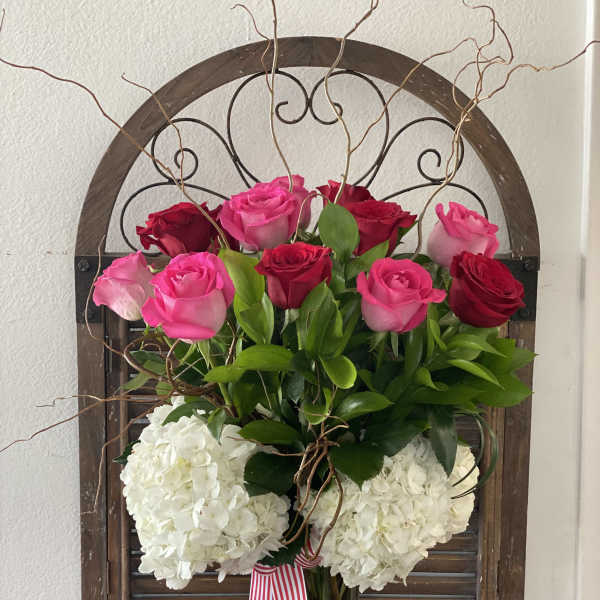 Pink and red roses with white hydrangeas in a glass vase