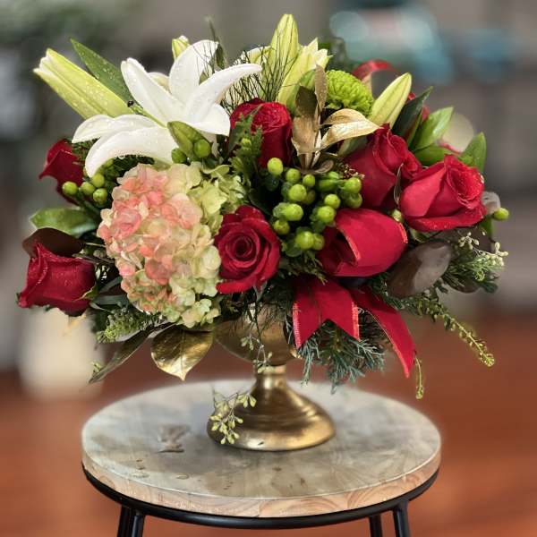 Red roses and white lilies arranged in a gold pedestal vase