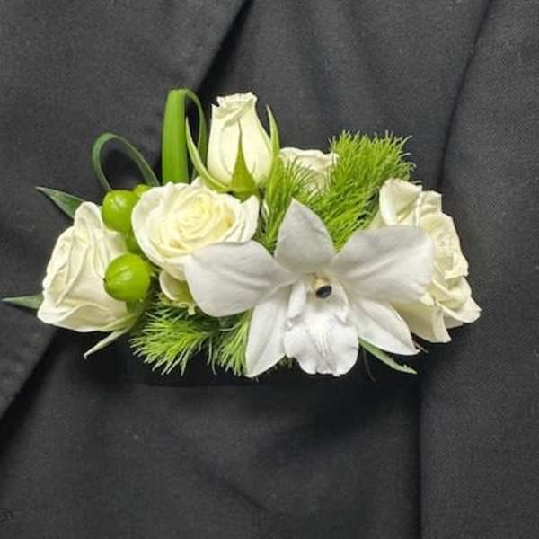 White rose and orchid boutonniere with green accents on a dark suit