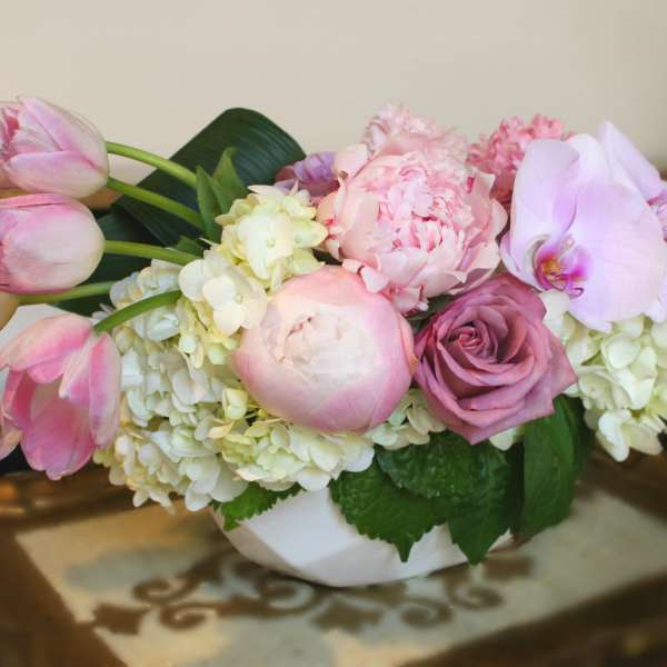 Pink tulips, roses, peonies, and orchids in a white bowl