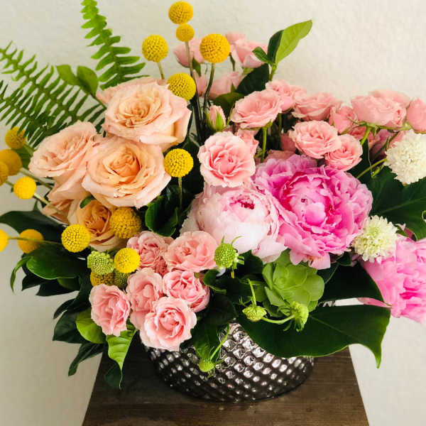 Pink and peach floral arrangement in a silver textured vase