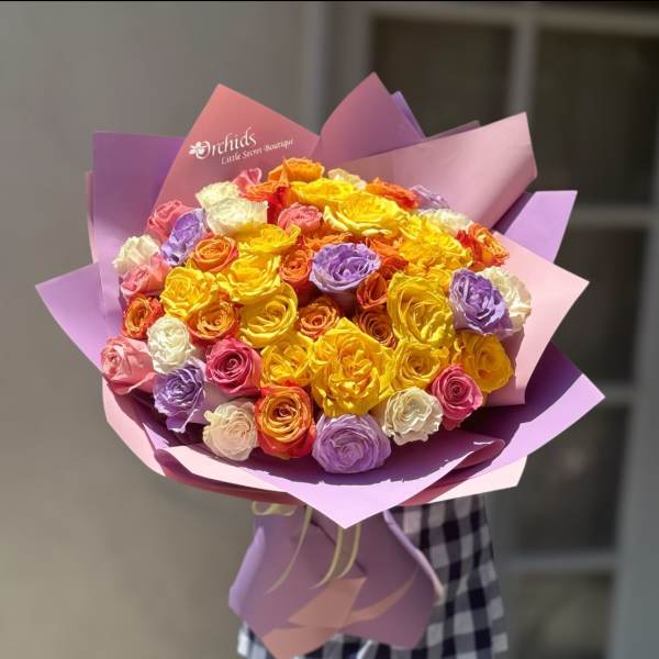 Large bouquet of multicolored roses wrapped in purple paper