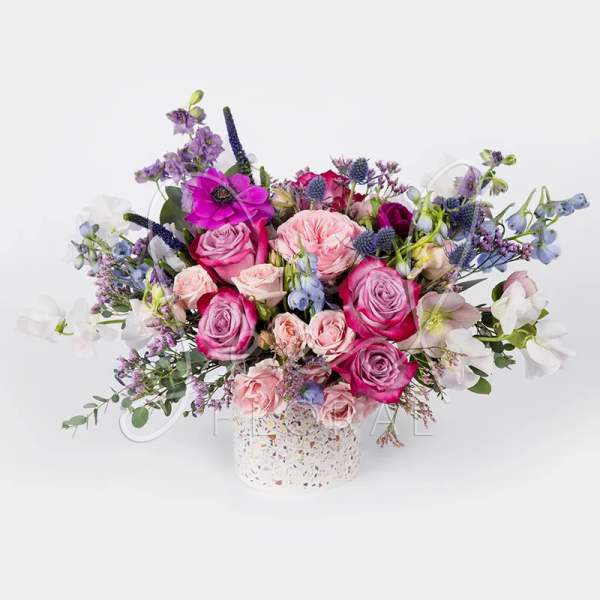 Pink and purple rose bouquet in a speckled white vase
