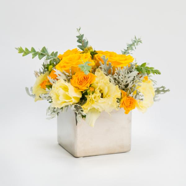 Yellow and cream flower arrangement in a square white vase