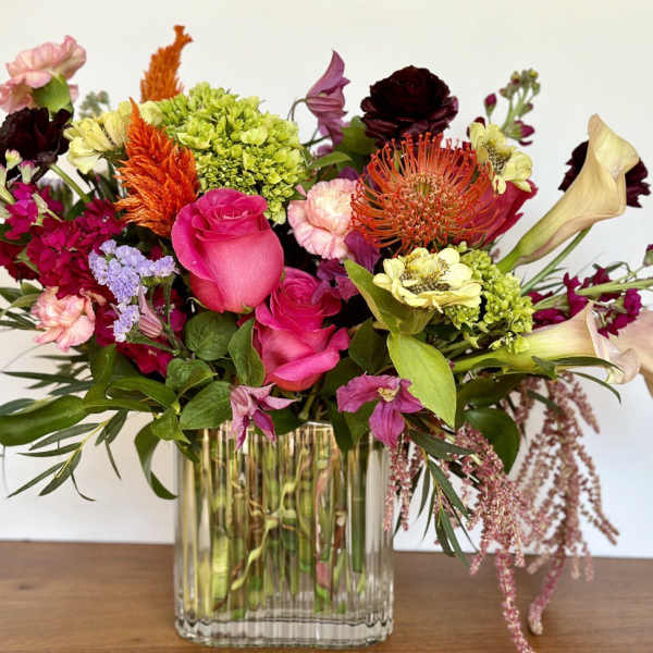 Mixed bouquet in a clear glass vase with pink, orange, and cream blooms