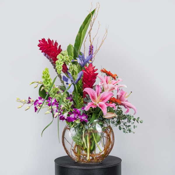 Tall mixed floral arrangement in a round glass vase